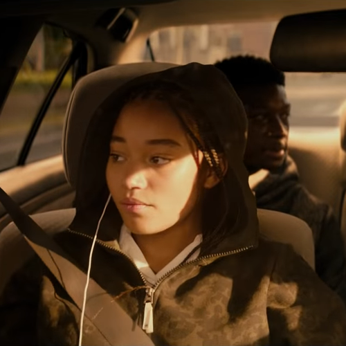 Ein Filmstill aus dem Film "The Hate U Give", Starr sitzt im Auto und trägt eine Kaputze und Kopfhörer.