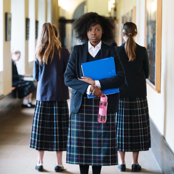 Eine schwarze Schülerin mit einem Afro blickt direkt in die Kamera.