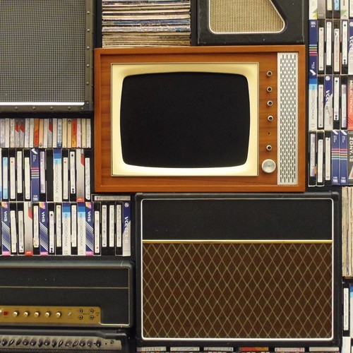 Ein alter Fernseher inmitten einer Regals voller Videokassetten.