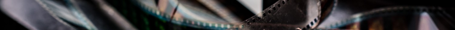 Der Flyer von FILM+SCHULE NRW liegt neben einem Filmstreifen und einer leuchtenden Filmklappe.