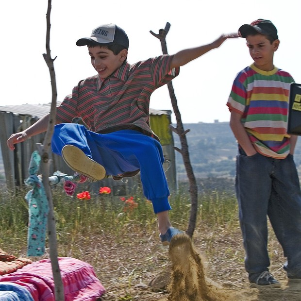 Ein Junge springt über eine Holzlatte.