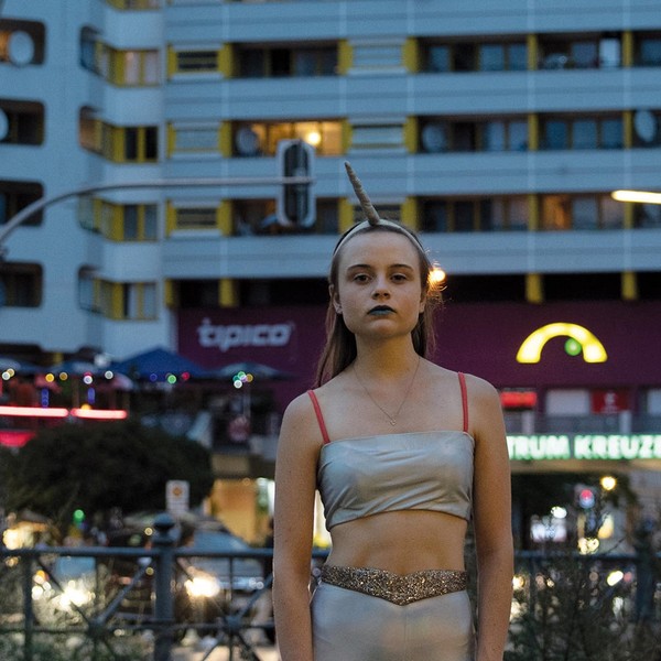 Eine junge Frau in einem Einhornkostüm steht vor einem Hochhaus.