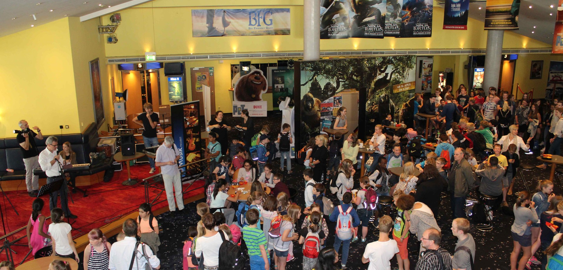 Eine große Gruppe Menschen in einem Kino-Foyer.