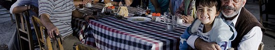 Eine türkische Familie sitzt an einem Tisch und schaut in die Kamera.