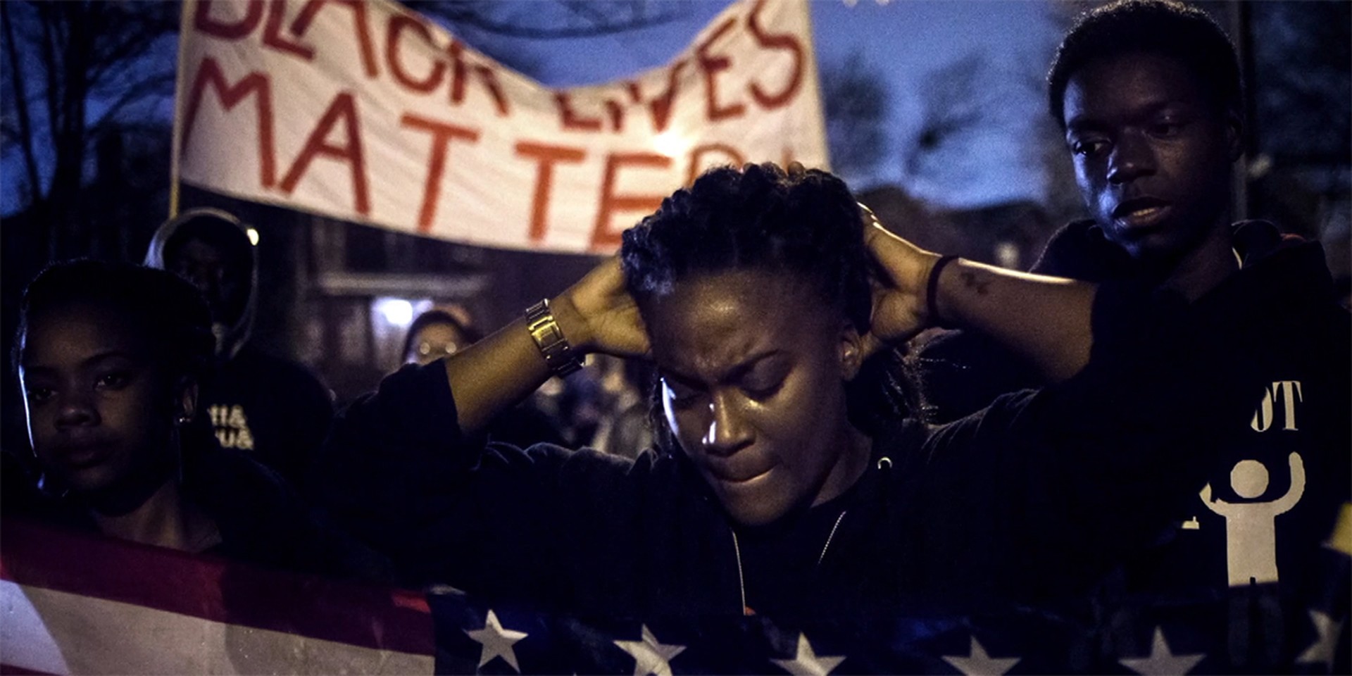 Ein Filmstills aus dem Film I am Not Your Negro, eine afroamerikanische Demonstrantin hält ihre Hände hinter dem Kopf verschränkt.