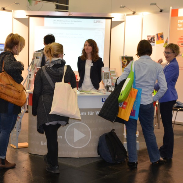 Eine Gruppe Menschen um einen LWL Stand versammelt, an dem eine Frau steht.