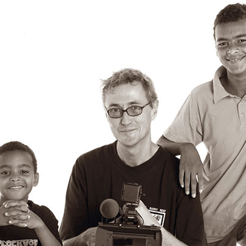 Ein Mann und zwei Jungen stehen vor einem weißen Hintergrund.