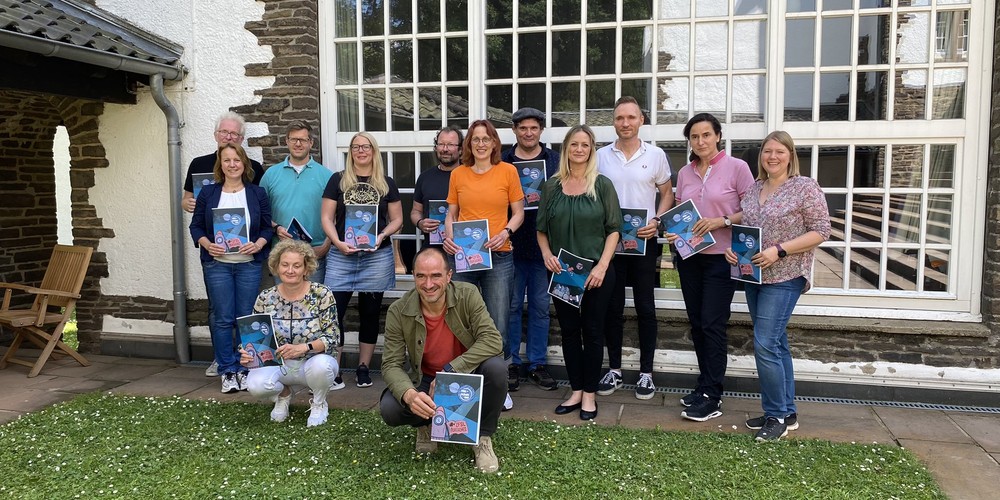 Gruppenfoto der ersten Runde der Basisqualifizierung: Menschen halten Urkunden.