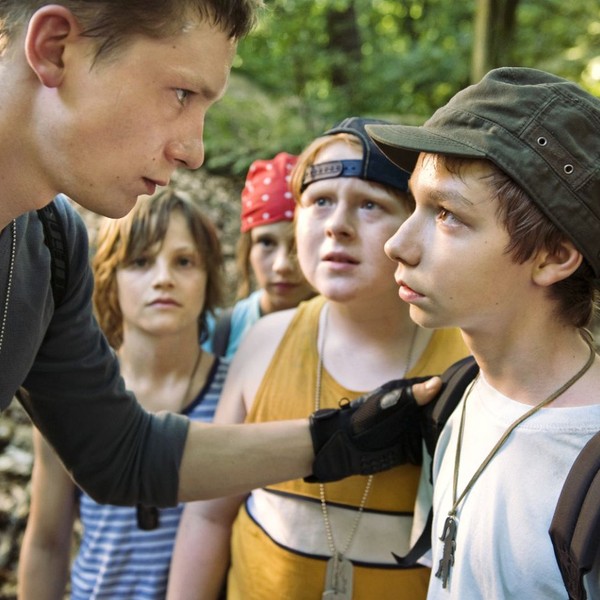 Ein Teenager und ein Junge stehen sich gegenüber, dahinter eine Gruppe Kinder.