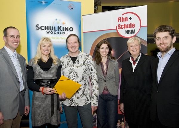 Eine Gruppe Menschen stehen vor Aufstellern von FILM+SCHULE NRW und den SchulKinoWochen.