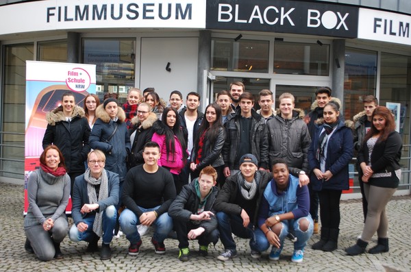 Eine Schulklasse posiert vor einem Kino.