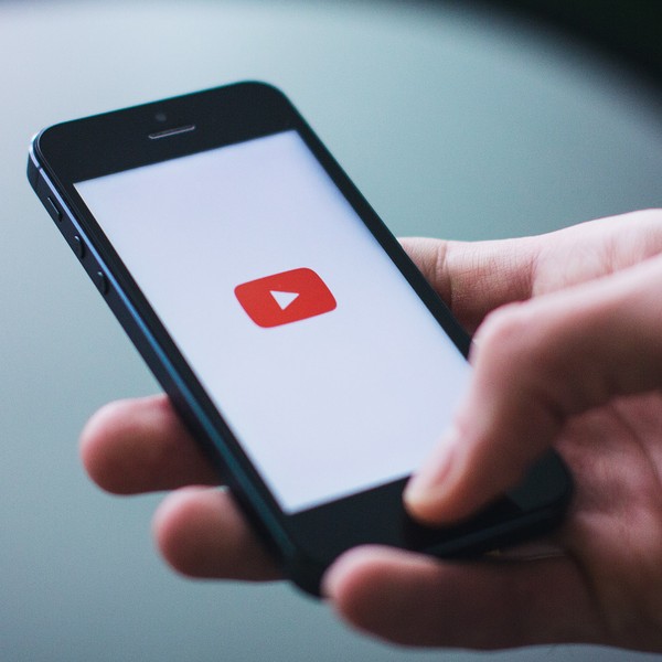 Ein Smartphone mit dem YouTube Logo auf weißem Hintergrund.