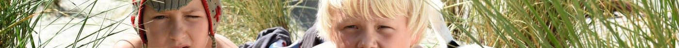 Filmstill aus dem Film "Rico, Oskar und die Tieferschatten": Rico und Oskar liegen am Strand hinter einer Düne, Rico macht ein Bild mit einer Kamera.